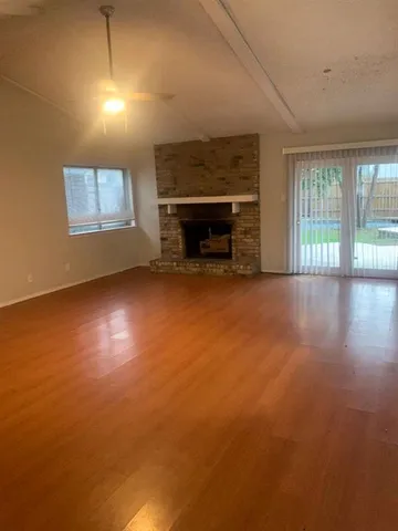 an empty room with windows and fireplace