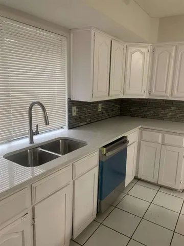 a kitchen with granite countertop white cabinets and sink