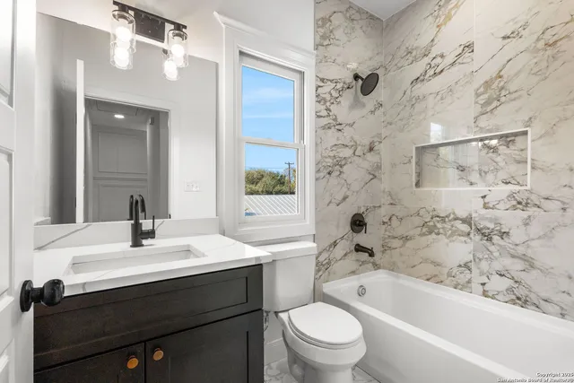 a bathroom with a bathtub sink vanity mirror and toilet