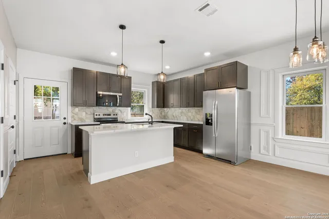 a kitchen with refrigerator a microwave and furniture