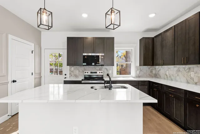 a kitchen with kitchen island granite countertop stainless steel appliances a sink cabinets and microwave
