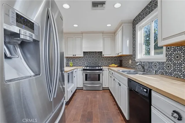 a kitchen with a refrigerator a sink and white cabinets