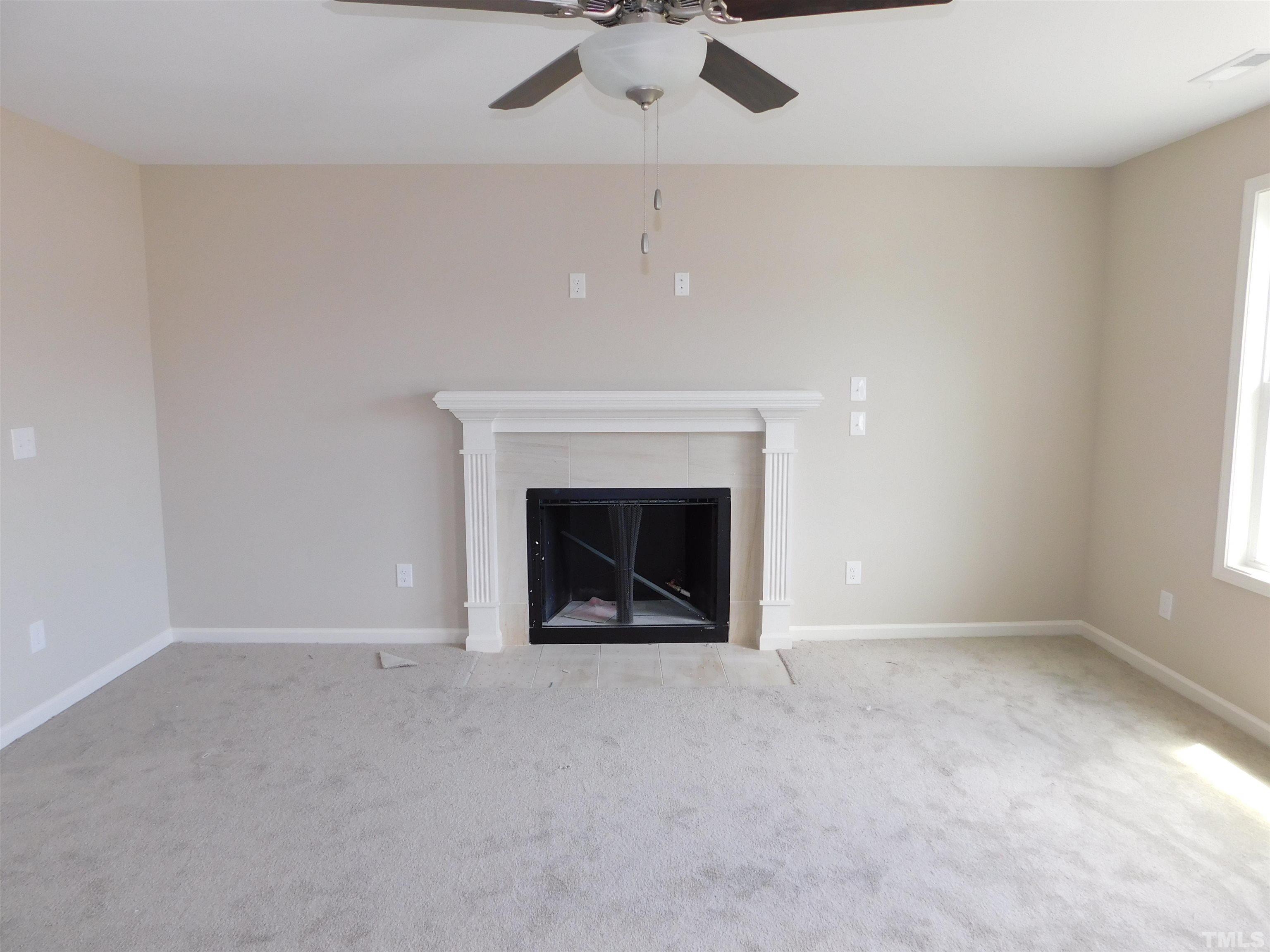 84 Kickoff Circle Benson, NC 27504 - Photo 5 of 21 an empty room with a fireplace and fan