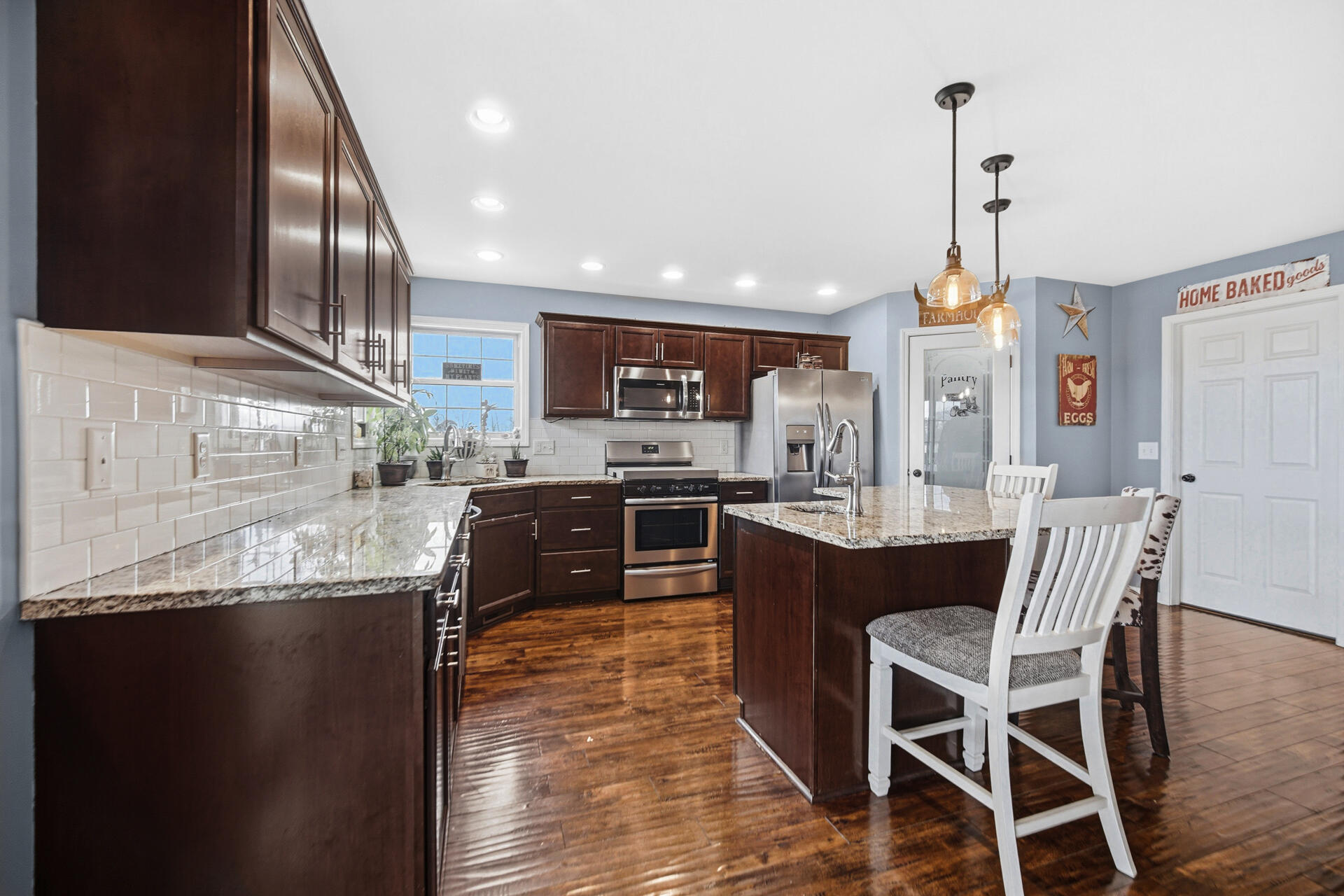 1913 Holly Street Southeast De Motte, IN 46310 - Photo 12 of 42 a kitchen with stainless steel appliances granite countertop a refrigerator a sink dishwasher a stove and a dining table with wooden floor