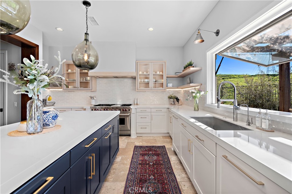 27 Pisano Street Ladera Ranch, CA 92694 - Photo 31 of 71 a kitchen with kitchen island stainless steel appliances a sink stove and white cabinets next to a window