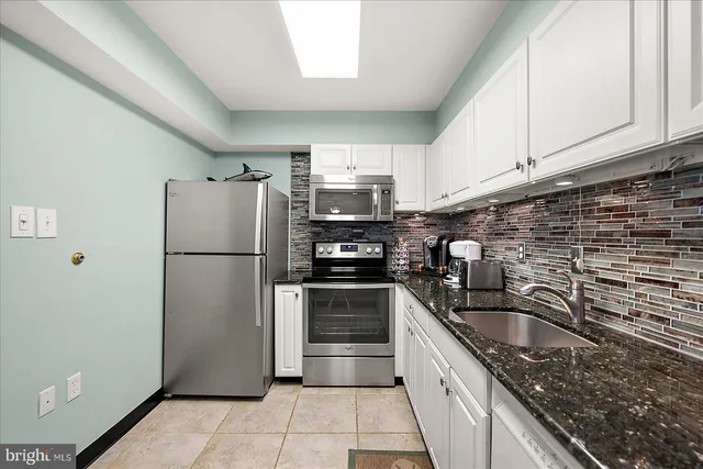 a kitchen with granite countertop a refrigerator sink and cabinets