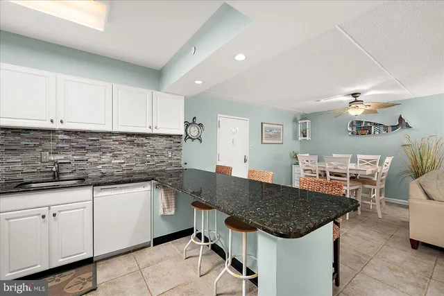 a kitchen with granite countertop a sink a stove cabinets counter space and a sink