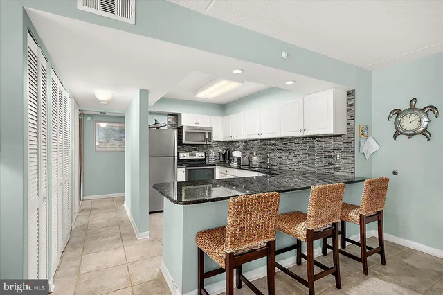 a kitchen with stainless steel appliances granite countertop a table and chairs in it