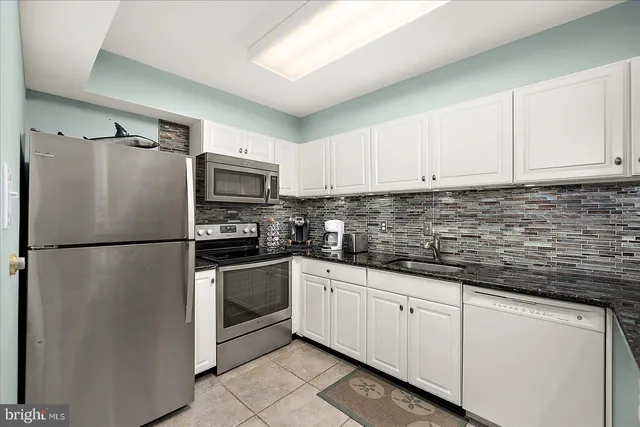 a kitchen with granite countertop white cabinets and refrigerator