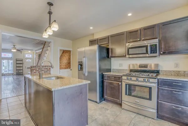 a kitchen with kitchen island granite countertop a stove and a sink