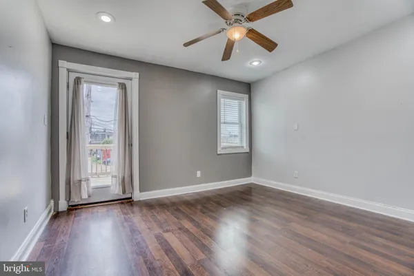 an empty room with wooden floor chandelier fan and windows