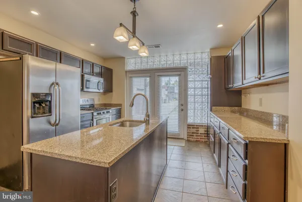 a kitchen with granite countertop a sink a counter top space appliances and cabinets