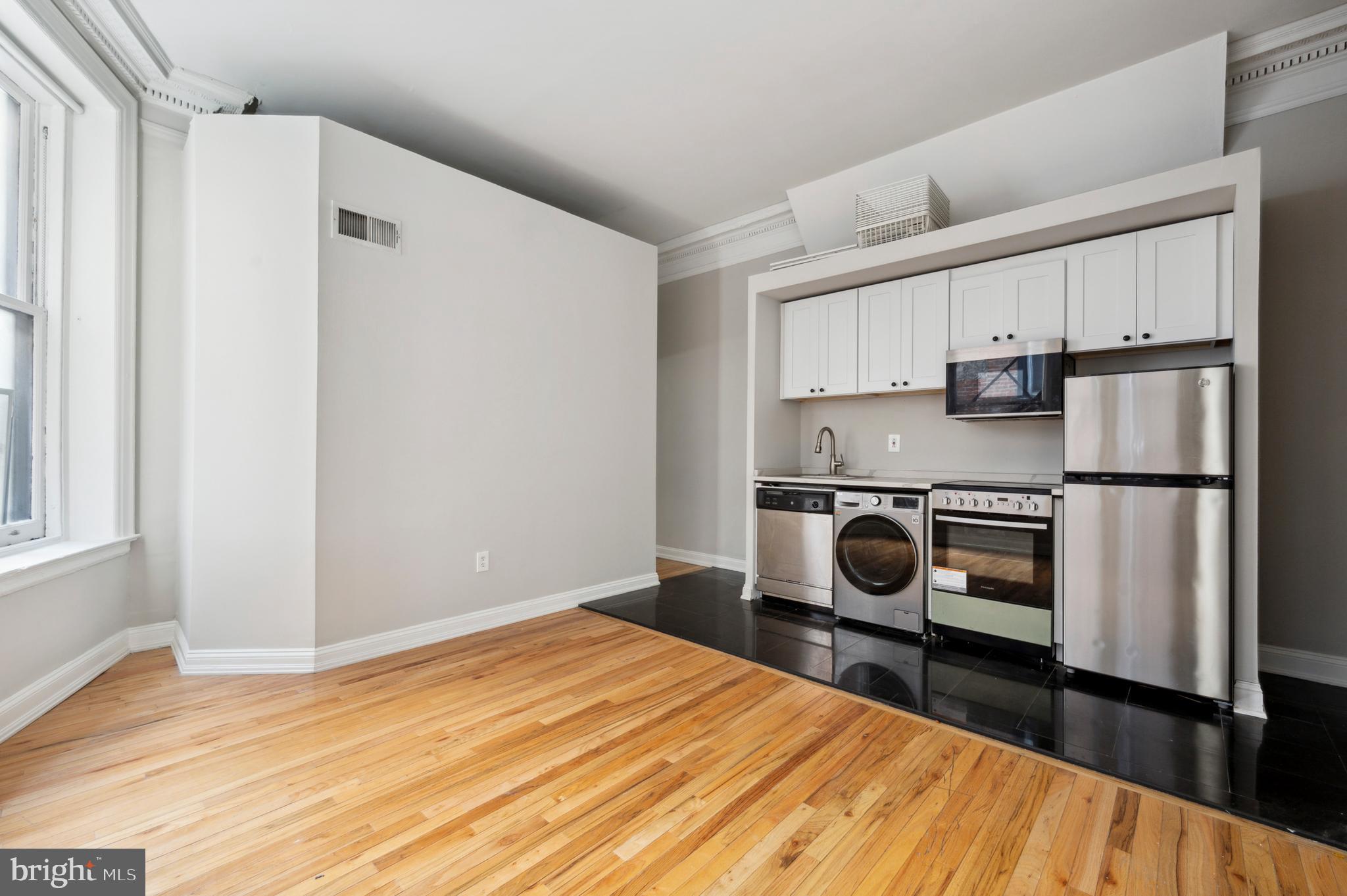 1723 Spruce Street Philadelphia, PA 19103 - Photo 12 of 24 a kitchen with a refrigerator a stove and white cabinets with wooden floor