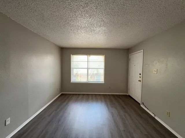 an empty room with wooden floor and window