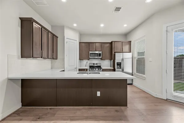 a view of kitchen with stainless steel appliances granite countertop sink stove top oven and cabinets