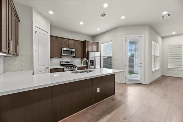 a kitchen with stainless steel appliances granite countertop a sink a stove and a refrigerator