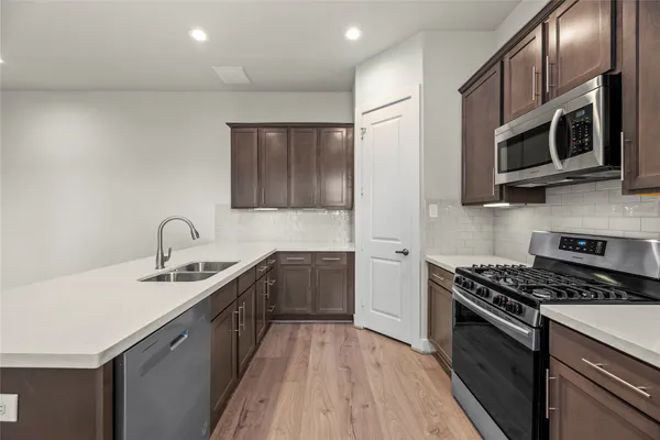 a kitchen with stainless steel appliances granite countertop a sink a stove top oven and wooden floors