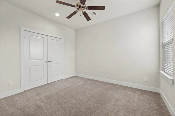 an empty room with windows and fan