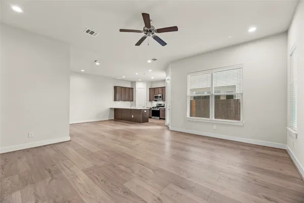 a view of empty room with wooden floor and ceiling fan