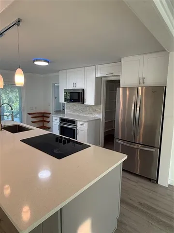 a kitchen with a refrigerator a stove top oven a sink and cabinets