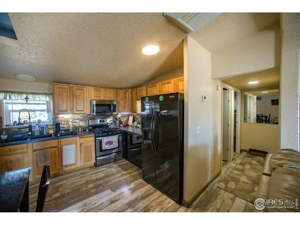a kitchen with stainless steel appliances kitchen island granite countertop a table chairs and a refrigerator