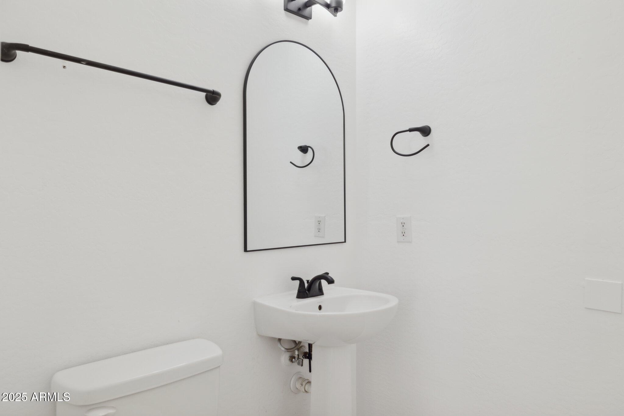 9951 West Bloch Road Tolleson, AZ 85353 - Photo 9 of 33 a bathroom with a sink a toilet and a mirror