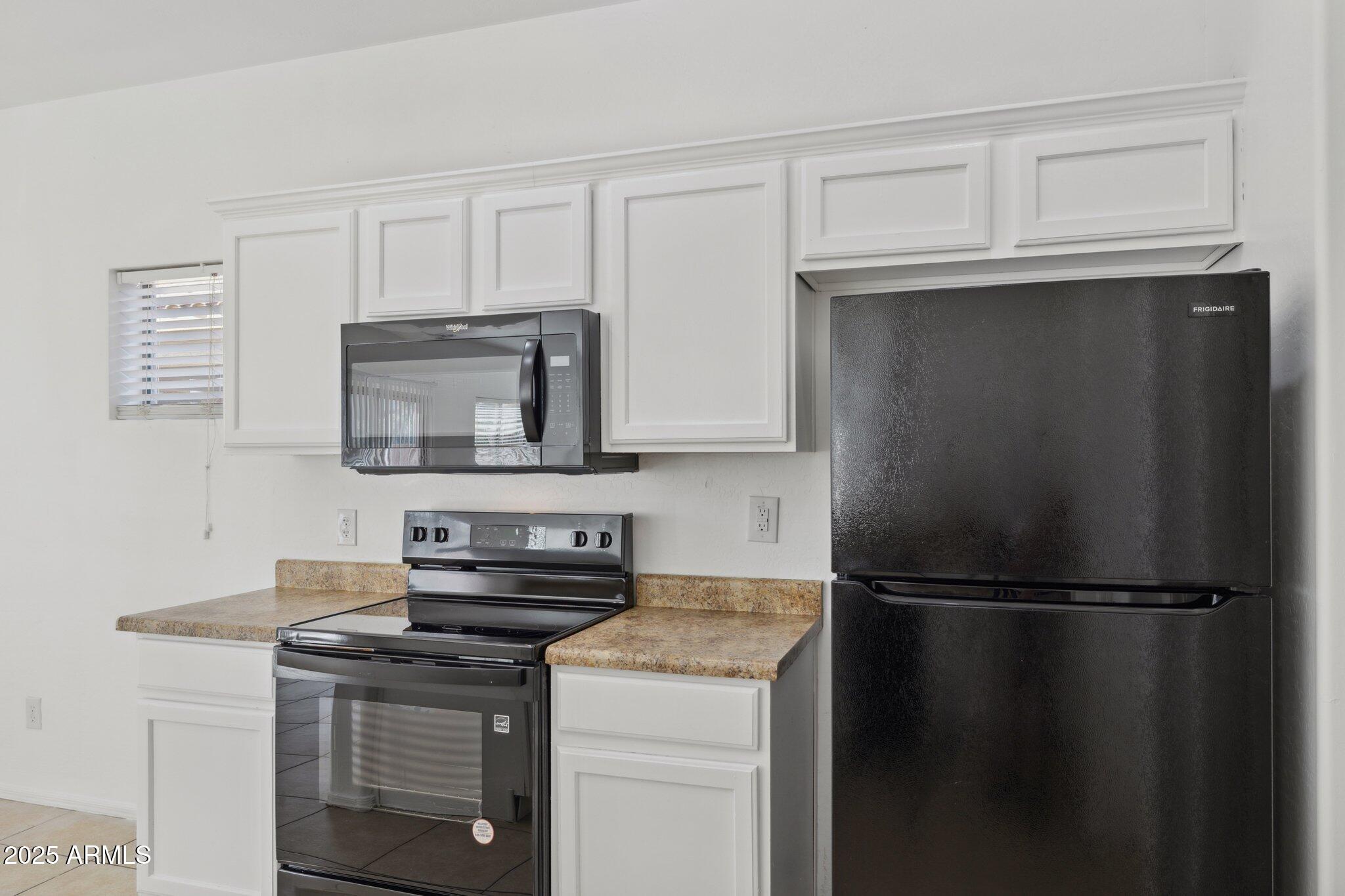 9951 West Bloch Road Tolleson, AZ 85353 - Photo 7 of 33 a kitchen with a refrigerator and a stove top oven