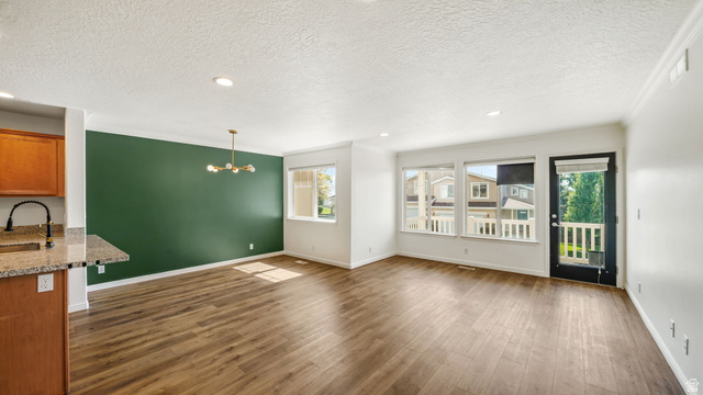 1285 Alpine Way Provo, UT 84606 - Photo 11 of 25 Open-concept living space with wood-finish flooring, a contemporary chandelier, multiple windows, and a glass-paneled door
