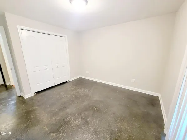 an empty room with wooden floor and closet area