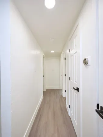 a view of a hallway with wooden floor and a bathroom
