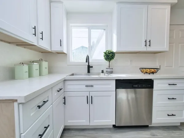 a kitchen with white cabinets and sink