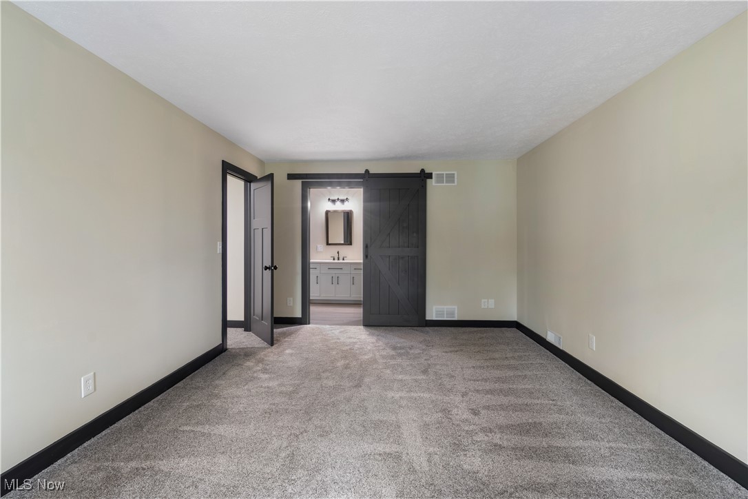 2201 Ridgewood Road Medina, OH 44256 - Photo 27 of 50 Carpeted spare room featuring a barn door and baseboards