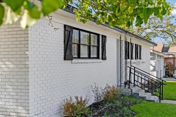 a view of a brick house with a small yard and a large tree
