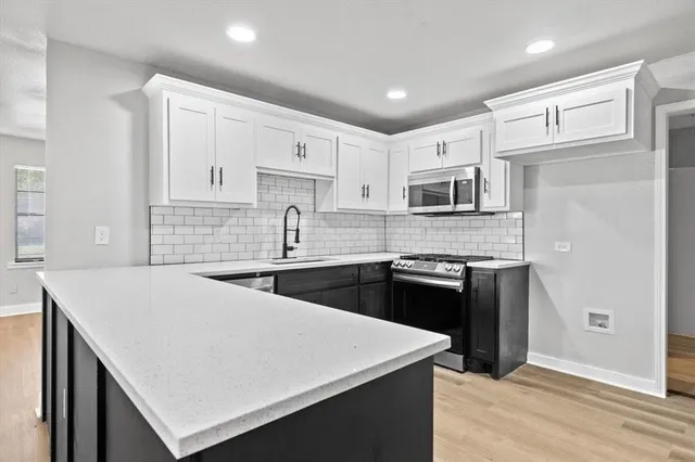 a kitchen with kitchen island a sink dishwasher stove and white cabinets