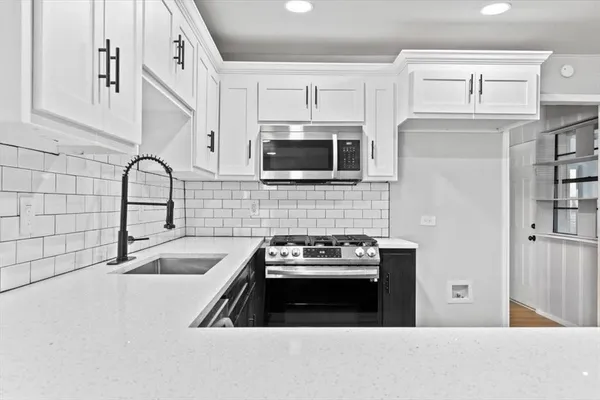 a kitchen with granite countertop a stove a sink and a microwave