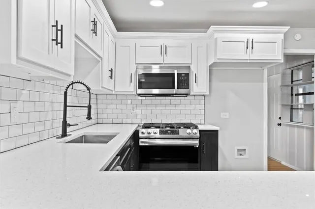 a kitchen with granite countertop a stove a sink and a microwave