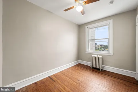 an empty room with wooden floor cabinet and windows