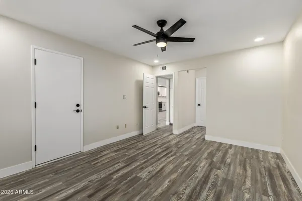 a view of empty room with wooden floor and ceiling fan