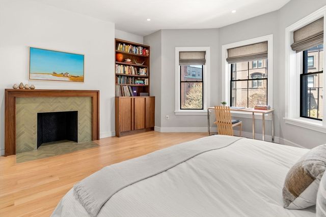 a bedroom with a large bed a fireplace and a window