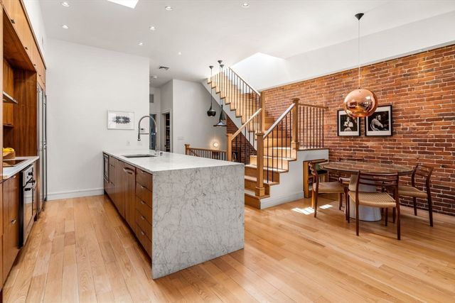 a living room with couches a flat screen tv and kitchen island with wooden floor