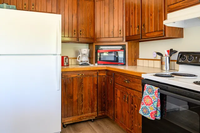 a kitchen with stainless steel appliances granite countertop wooden floors and wooden cabinets