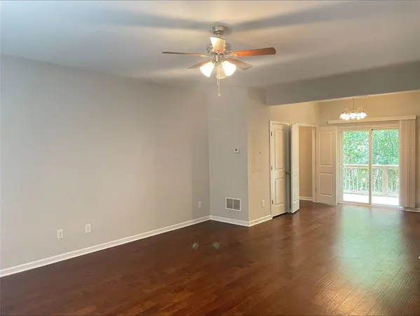a view of an empty room with wooden floor and a window