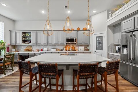 a kitchen with stainless steel appliances granite countertop a table chairs stove refrigerator and cabinets