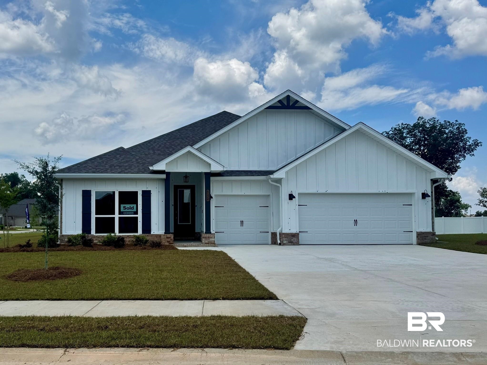 Modern farmhouse exterior with white board and batten siding, dark shingle roof, stone accents, two-car garage, and a concrete driveway