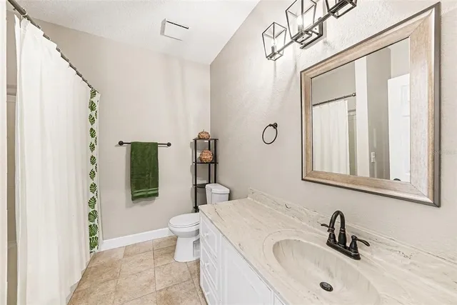 a bathroom with a sink a toilet and shower curtain