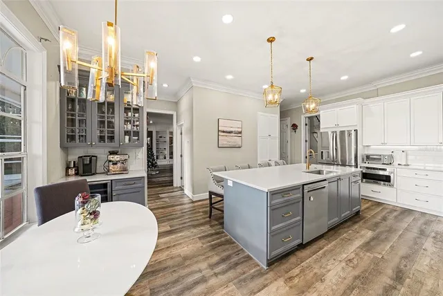 a large kitchen with kitchen island a stove a sink a oven and a dining table with wooden floor