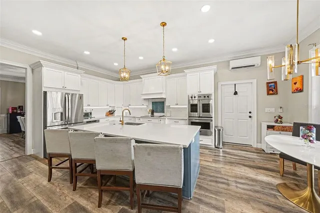 a kitchen with stainless steel appliances kitchen island granite countertop a table chairs and a refrigerator