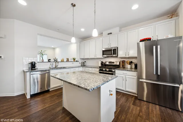 a kitchen with stainless steel appliances granite countertop a refrigerator a stove a sink dishwasher and a refrigerator with wooden floor