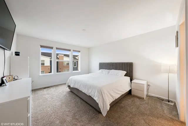 a large bed sitting in a bedroom next to a window with pc on the dresser