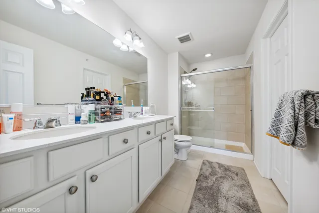a spacious bathroom with a double vanity sink toilet mirror and shower